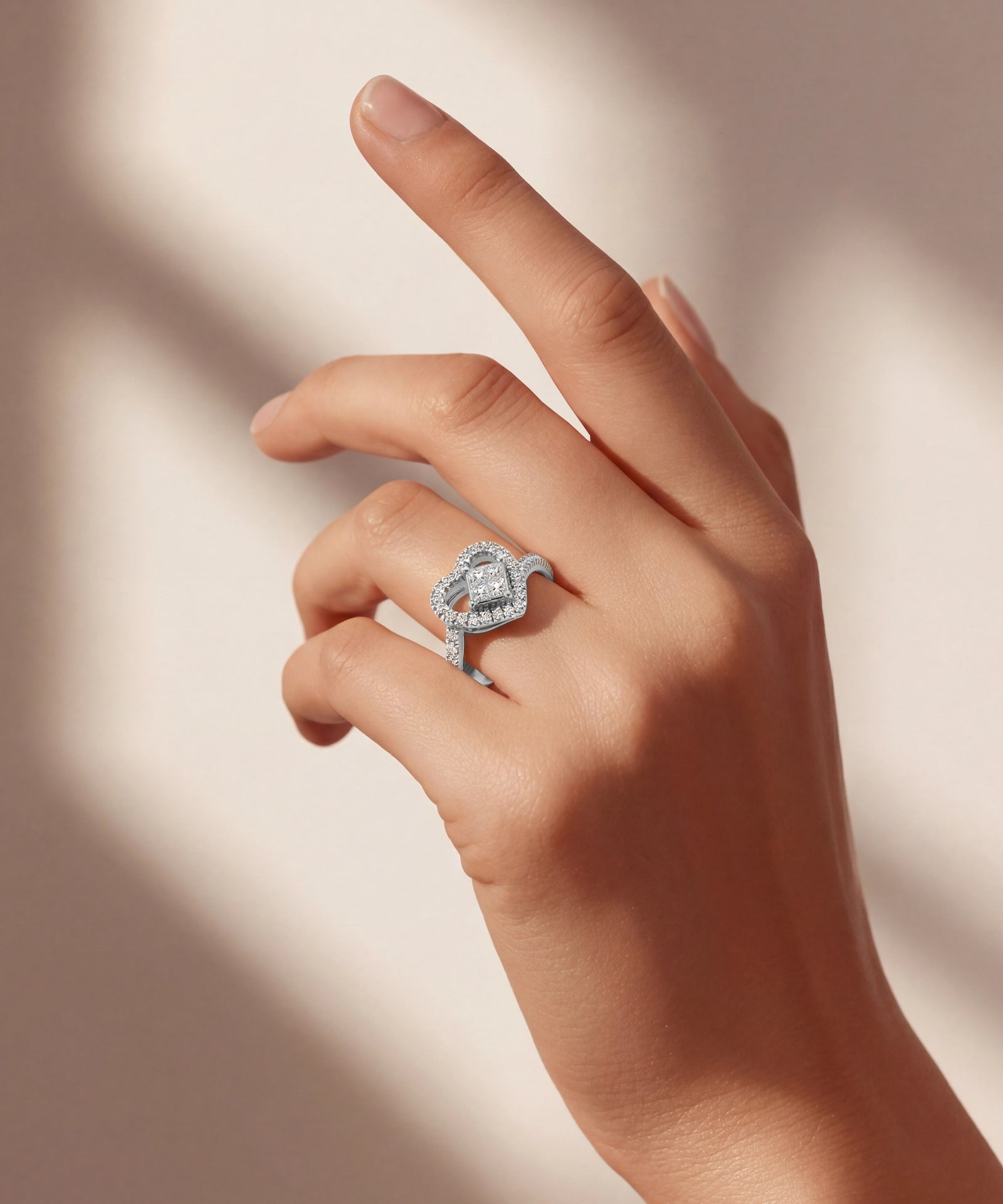 Hand wearing a diamond ring on a soft beige background