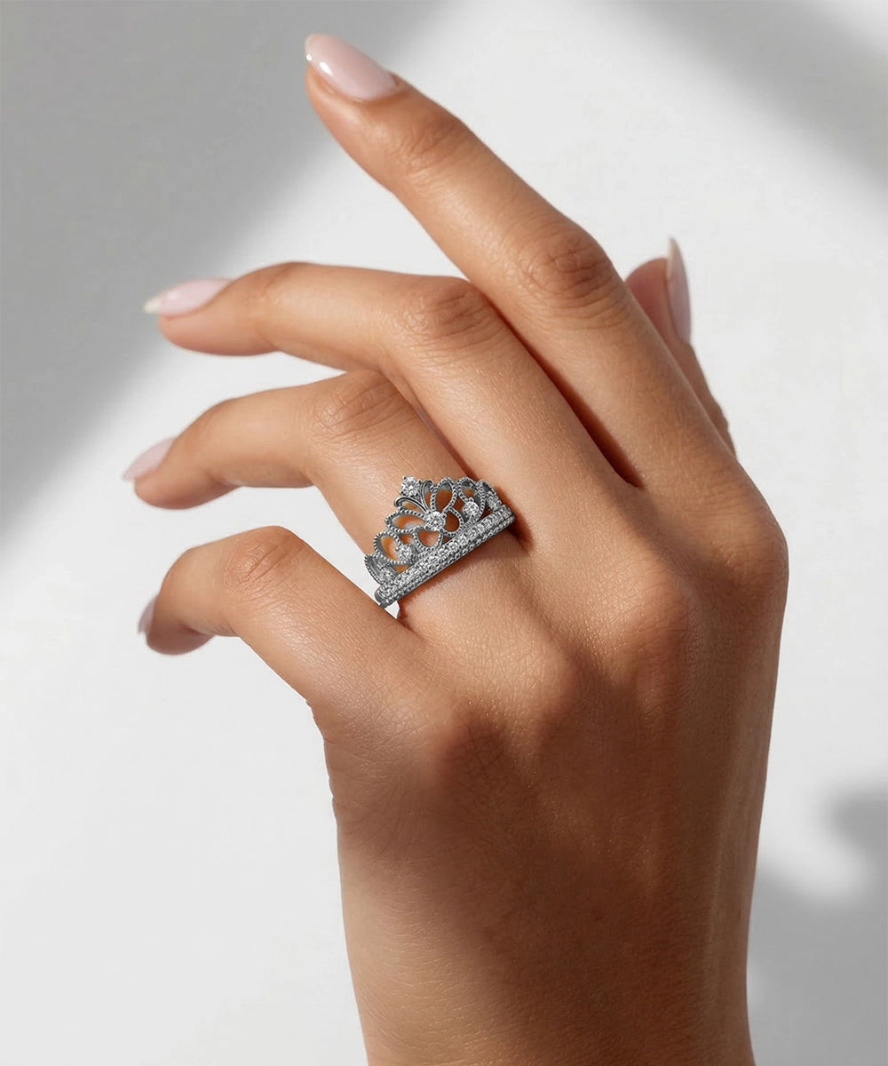 Hand wearing a silver ring with intricate design on a neutral background