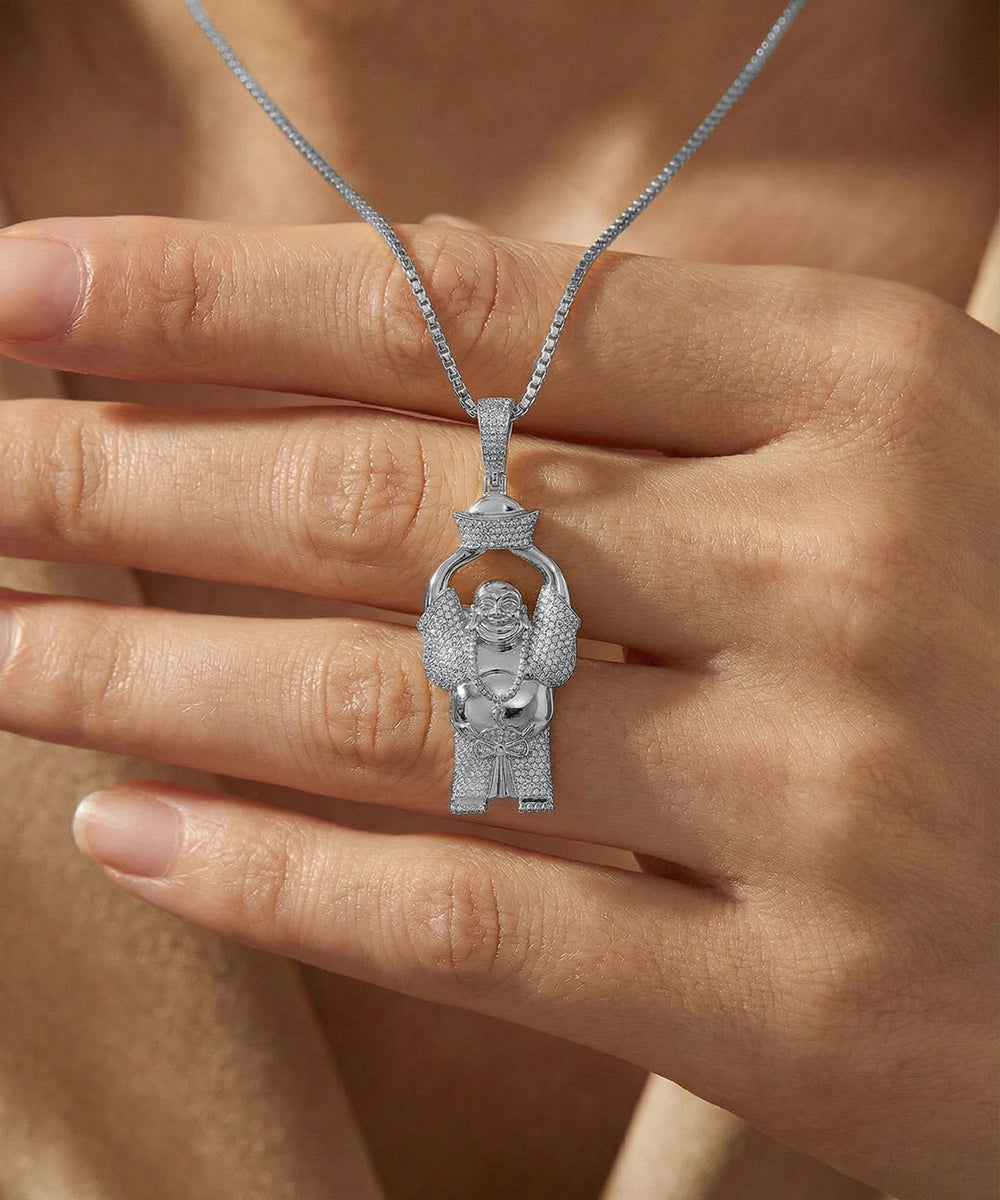 Silver pendant with a figure held by a hand against a neutral background