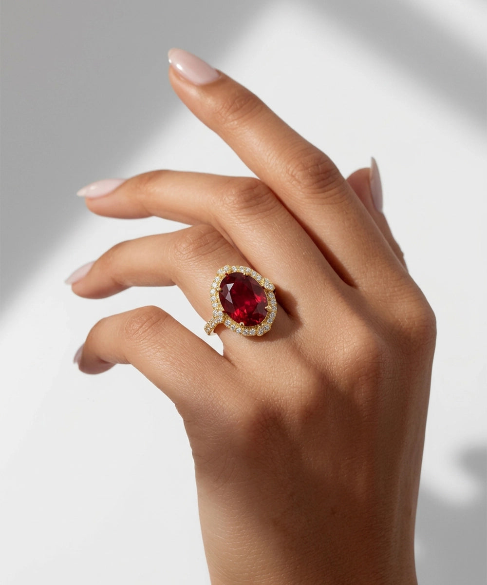 Hand wearing a ring with a red gemstone on a white background