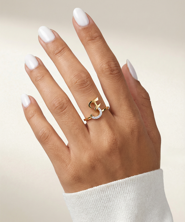 Hand wearing a gold ring with a diamond on a neutral background