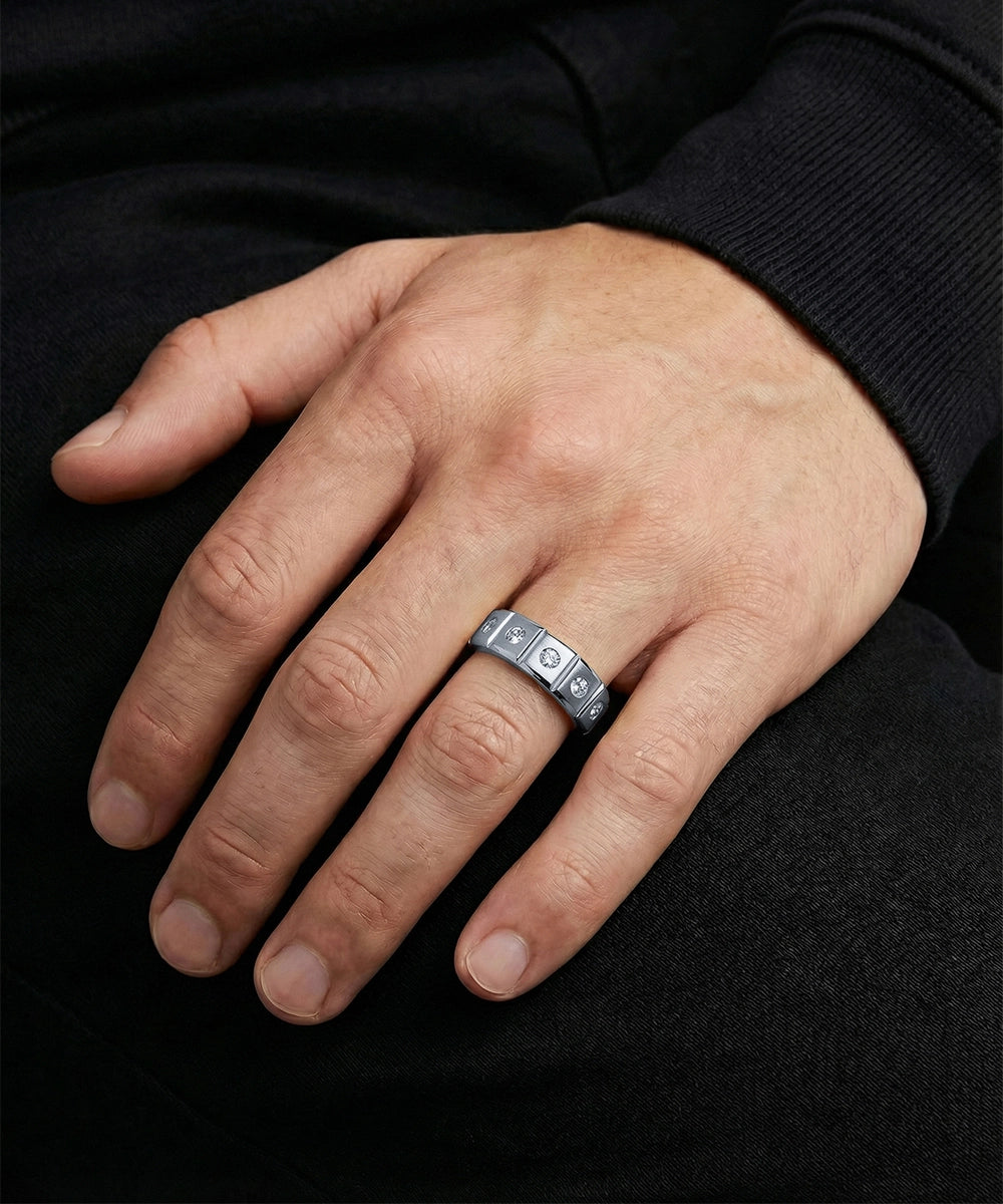 Hand wearing a silver ring with embedded stones on a black background