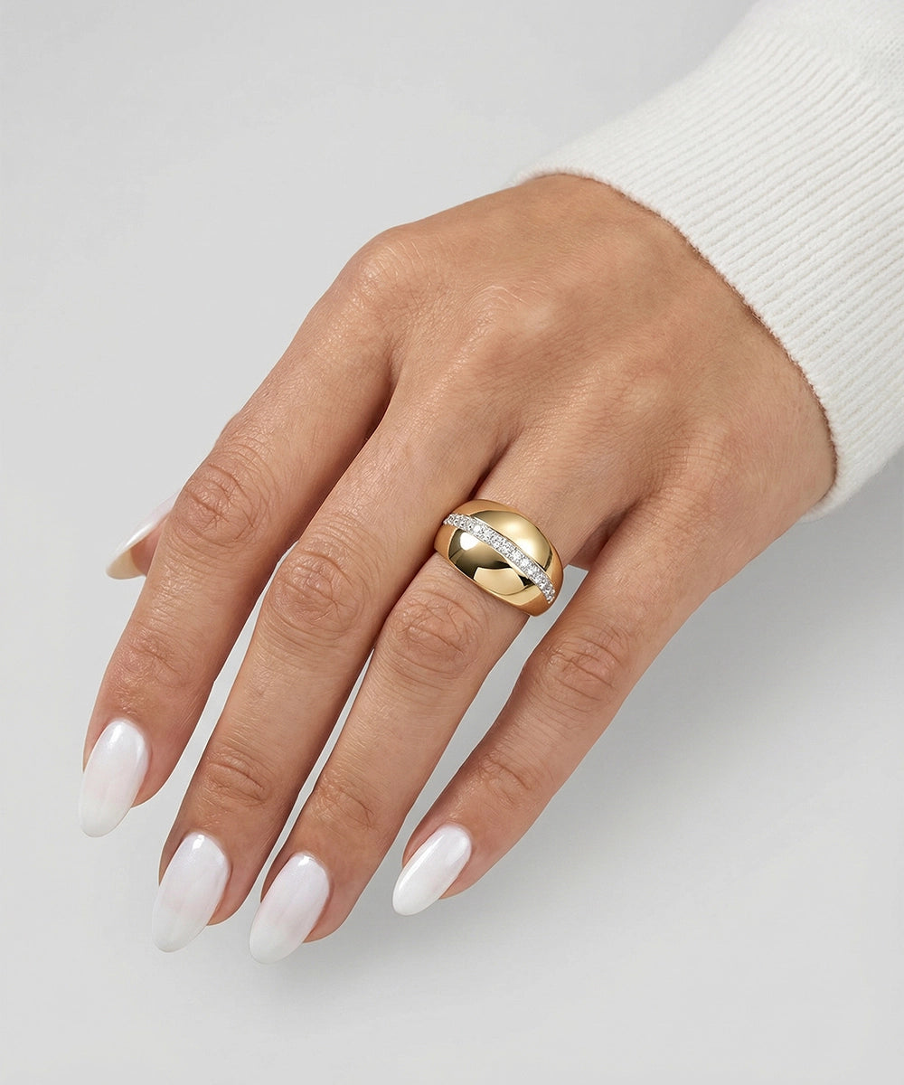 Hand wearing a gold ring with a diamond on a light gray background