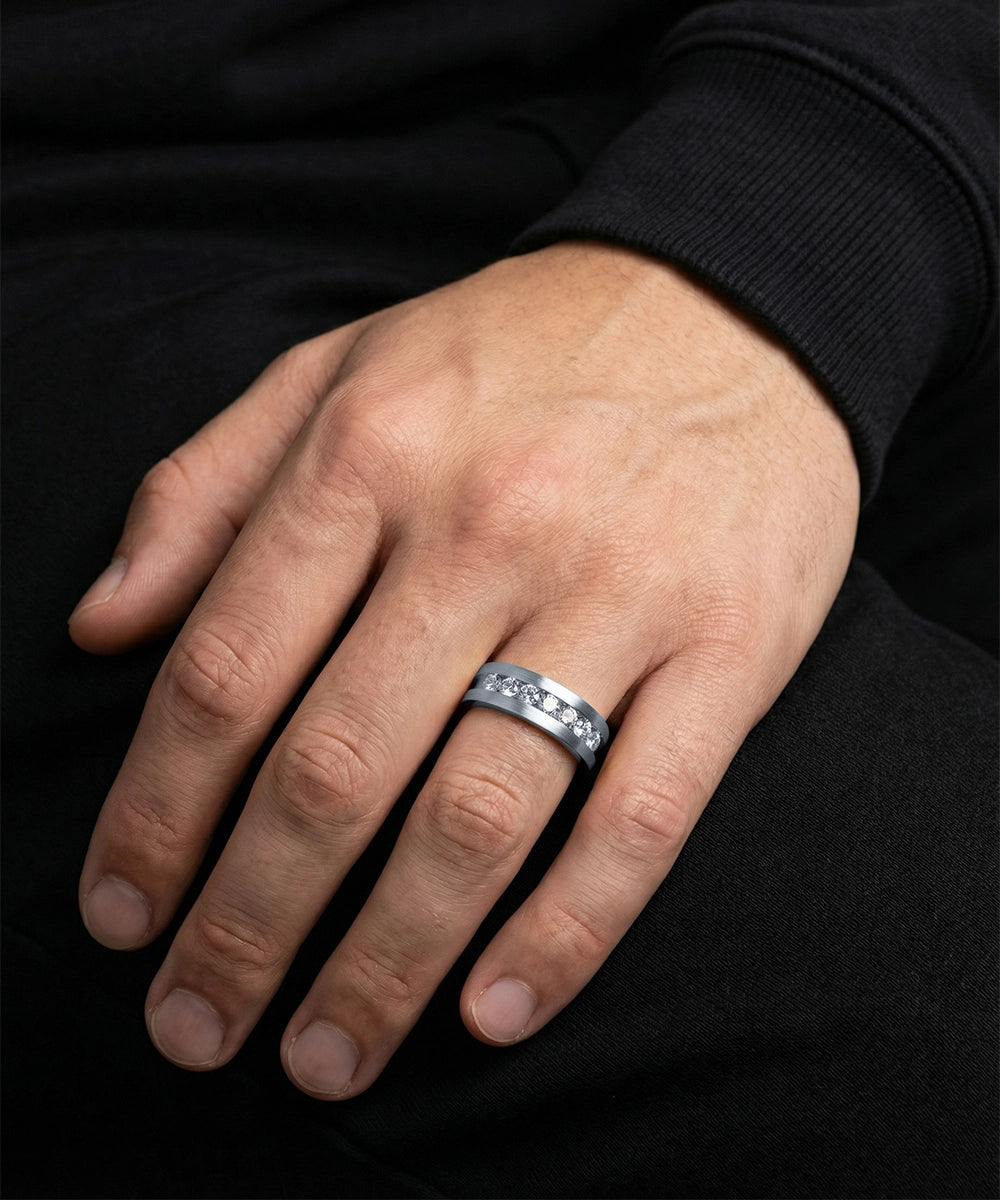 Hand wearing a silver ring with black background