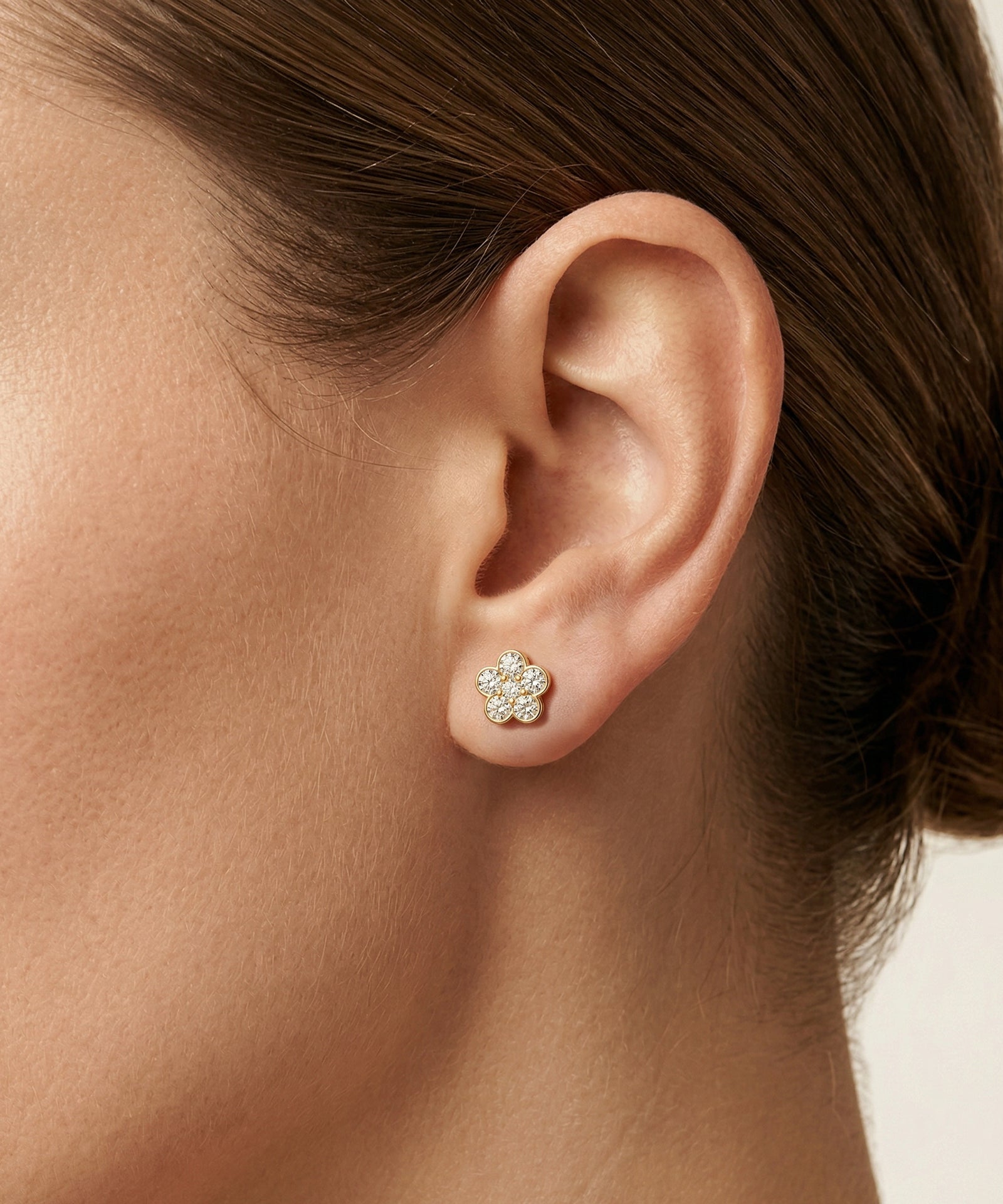 Close-up of an ear wearing a diamond stud earring with a blurred background