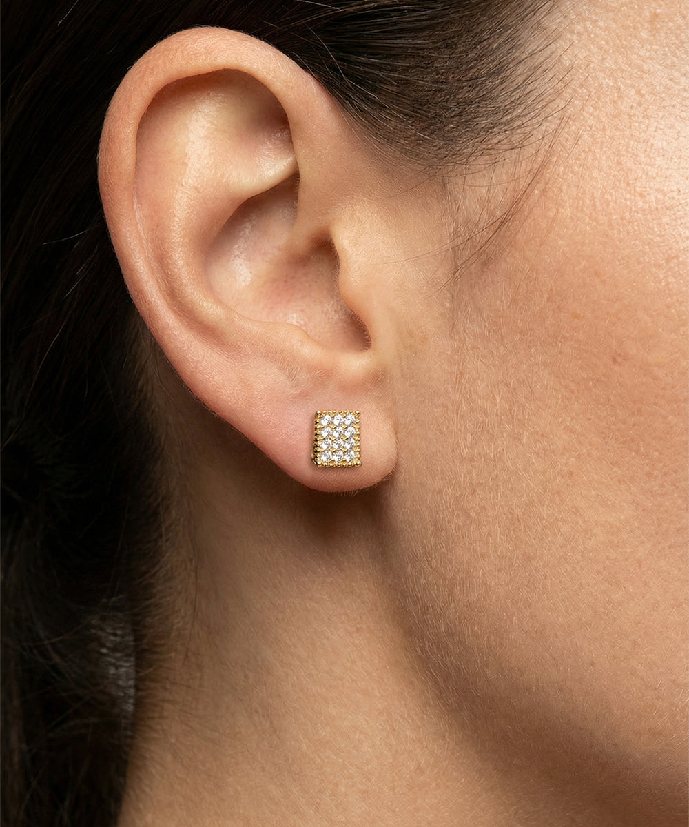 Close-up of an ear wearing a gold earring with clear stones.
