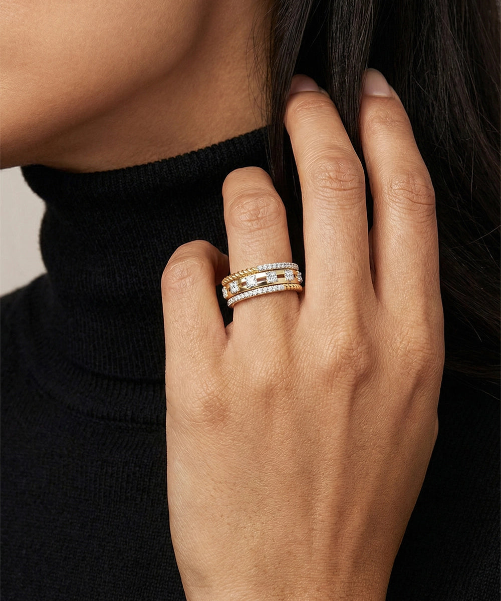 Hand wearing a stack of gold rings with a blurred background
