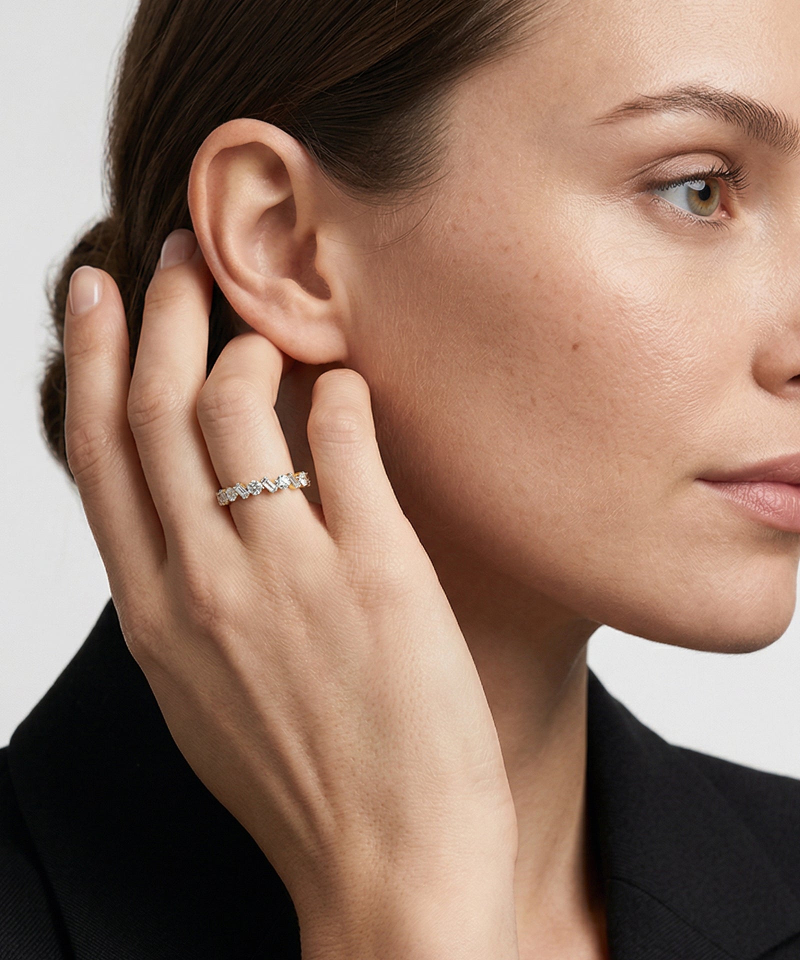 Close-up of a woman wearing a diamond ring, with a neutral background