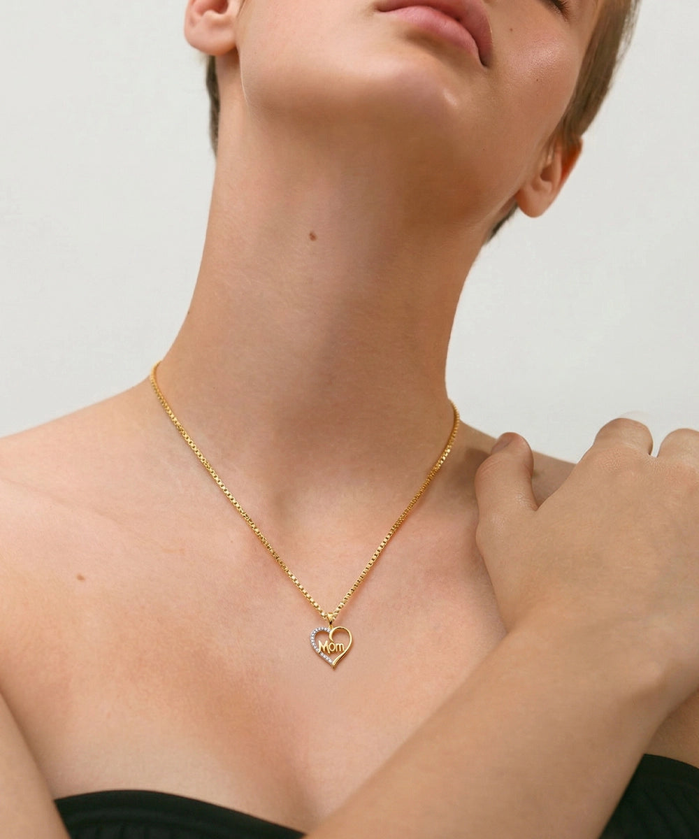 Gold necklace with a heart pendant worn by a person on a plain background