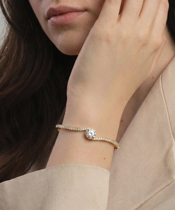 Close-up of a woman's wrist wearing a delicate gold bracelet with a diamond.