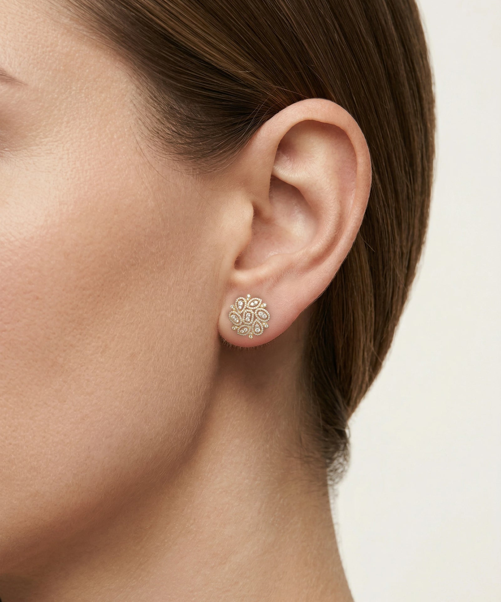 Close-up of a person wearing a silver earring with a floral design.