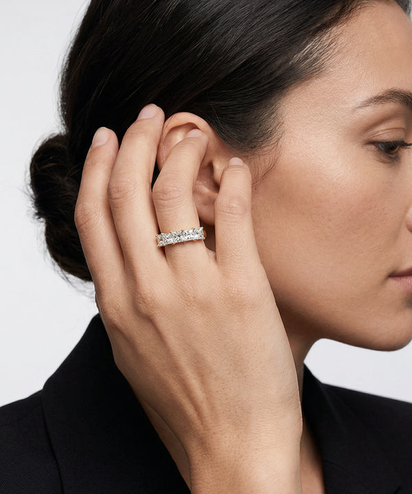 Close-up of a woman wearing a diamond ring on her hand against a neutral background