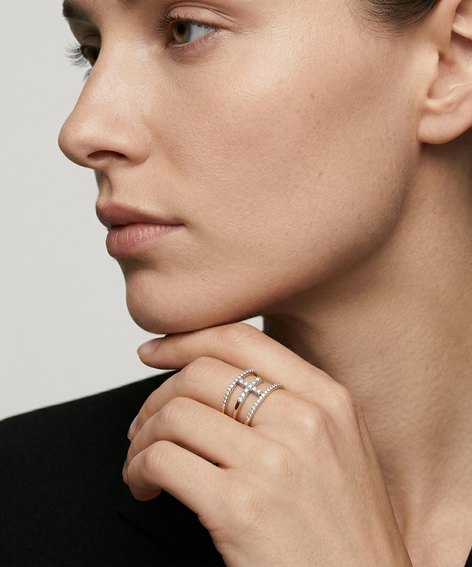 Close-up of a woman's face wearing a ring with a neutral background