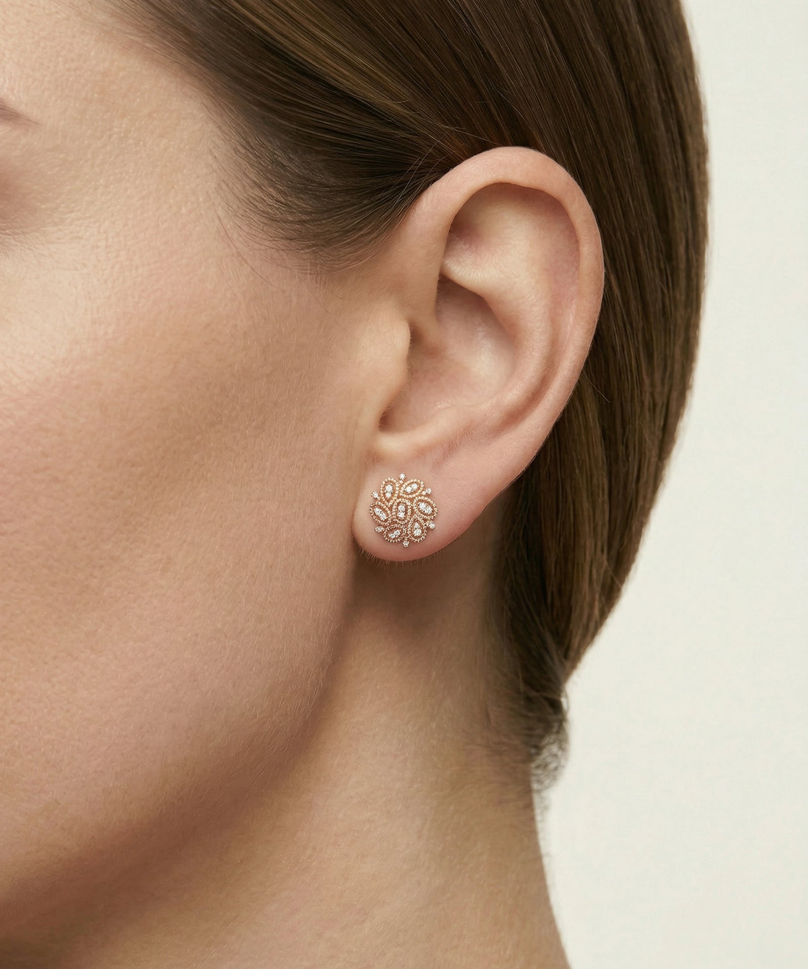 Close-up of an ear wearing a small earring with a neutral background