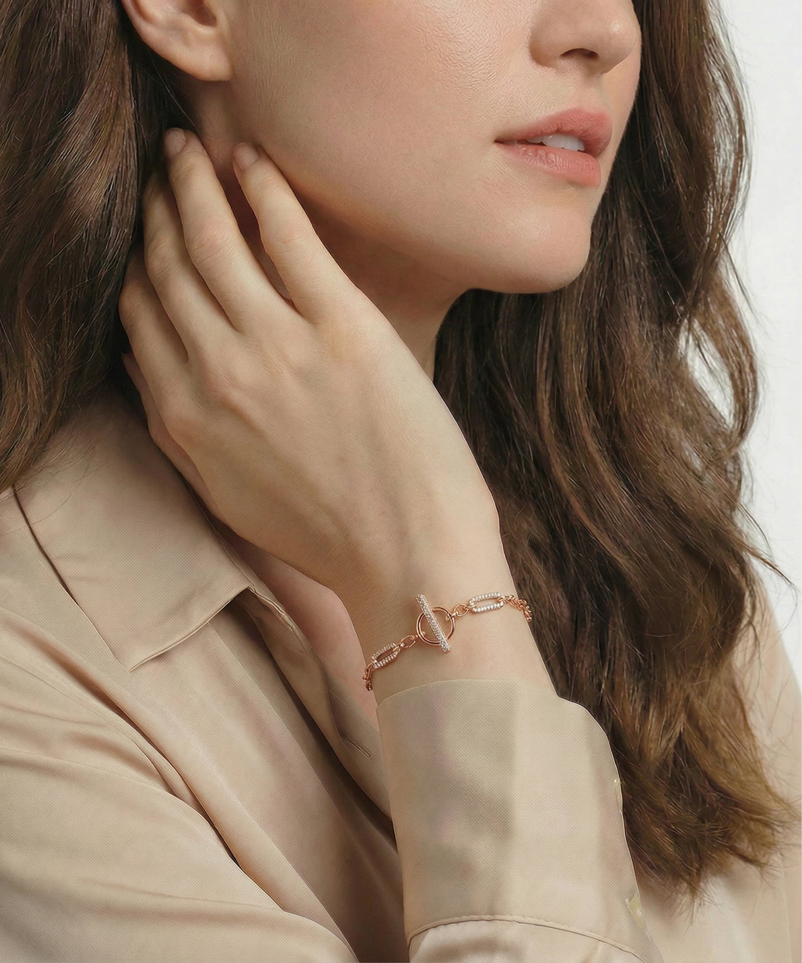 Woman wearing a rose gold bracelet with a heart design on a neutral background