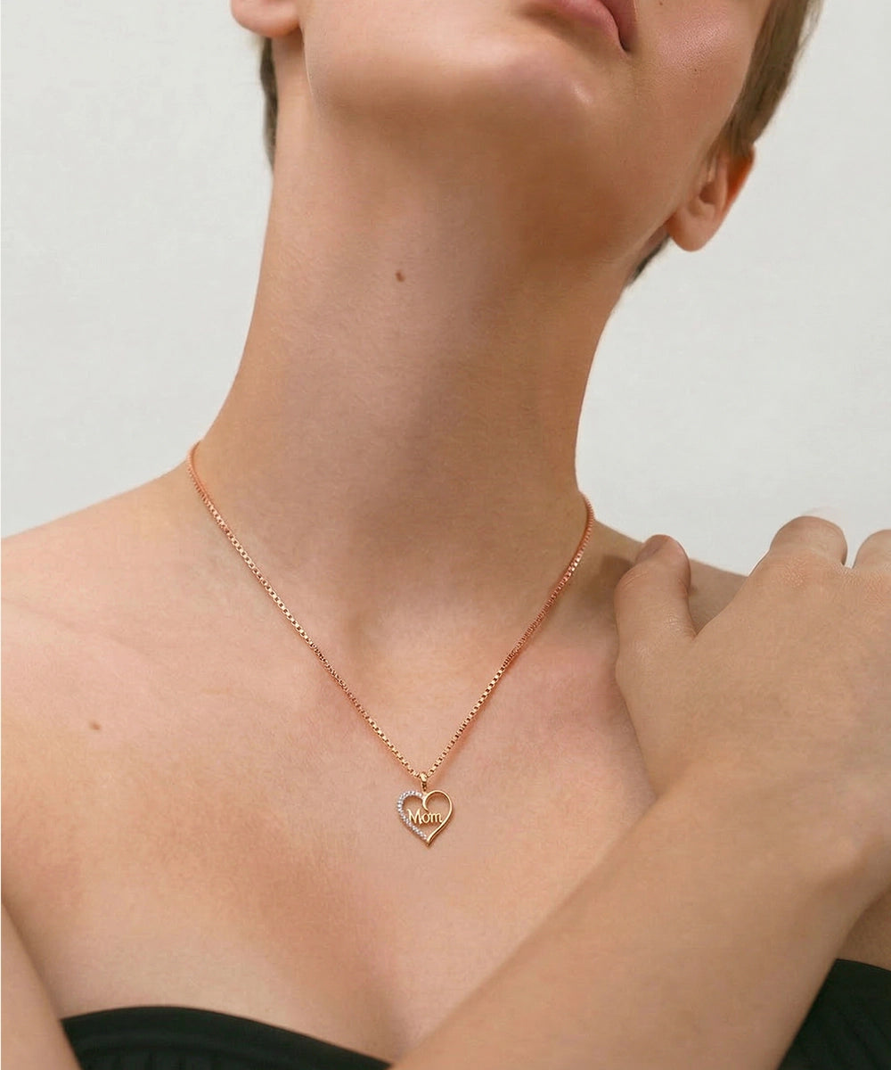 Rose gold necklace with a heart pendant worn by a person against a neutral background