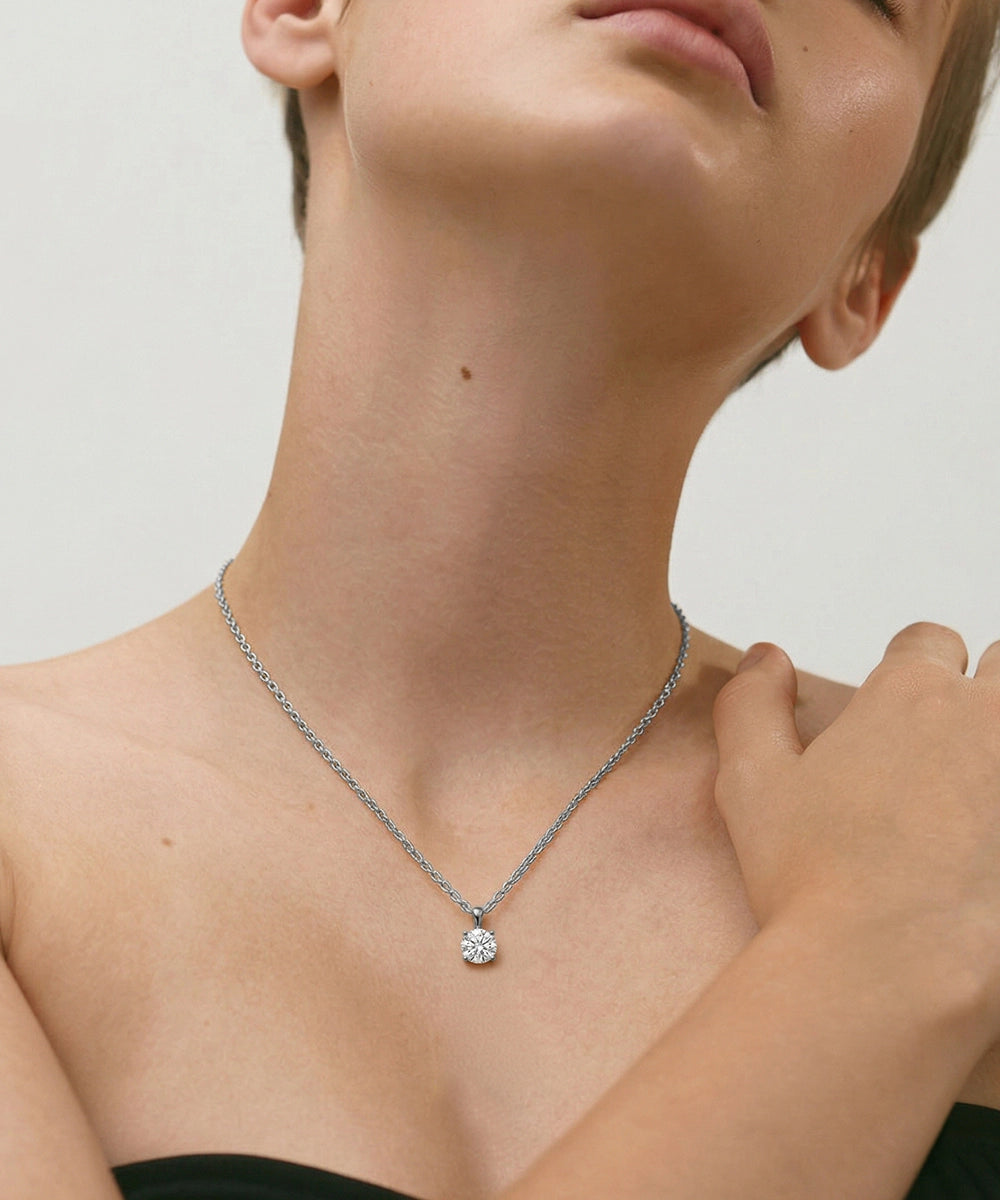Necklace with a diamond pendant worn by a person on a neutral background