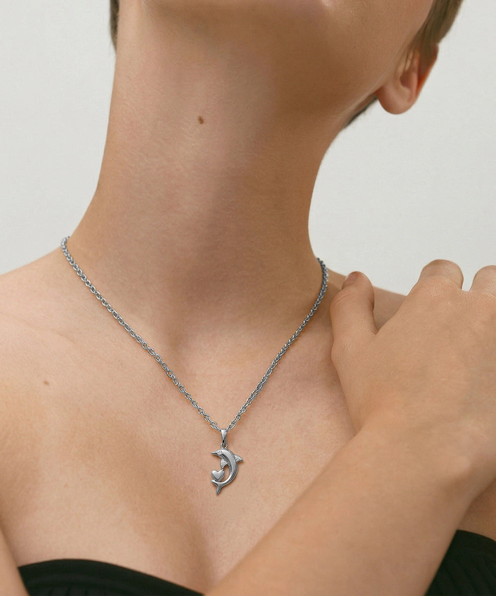 Person wearing a silver necklace with a crescent moon pendant on a neutral background