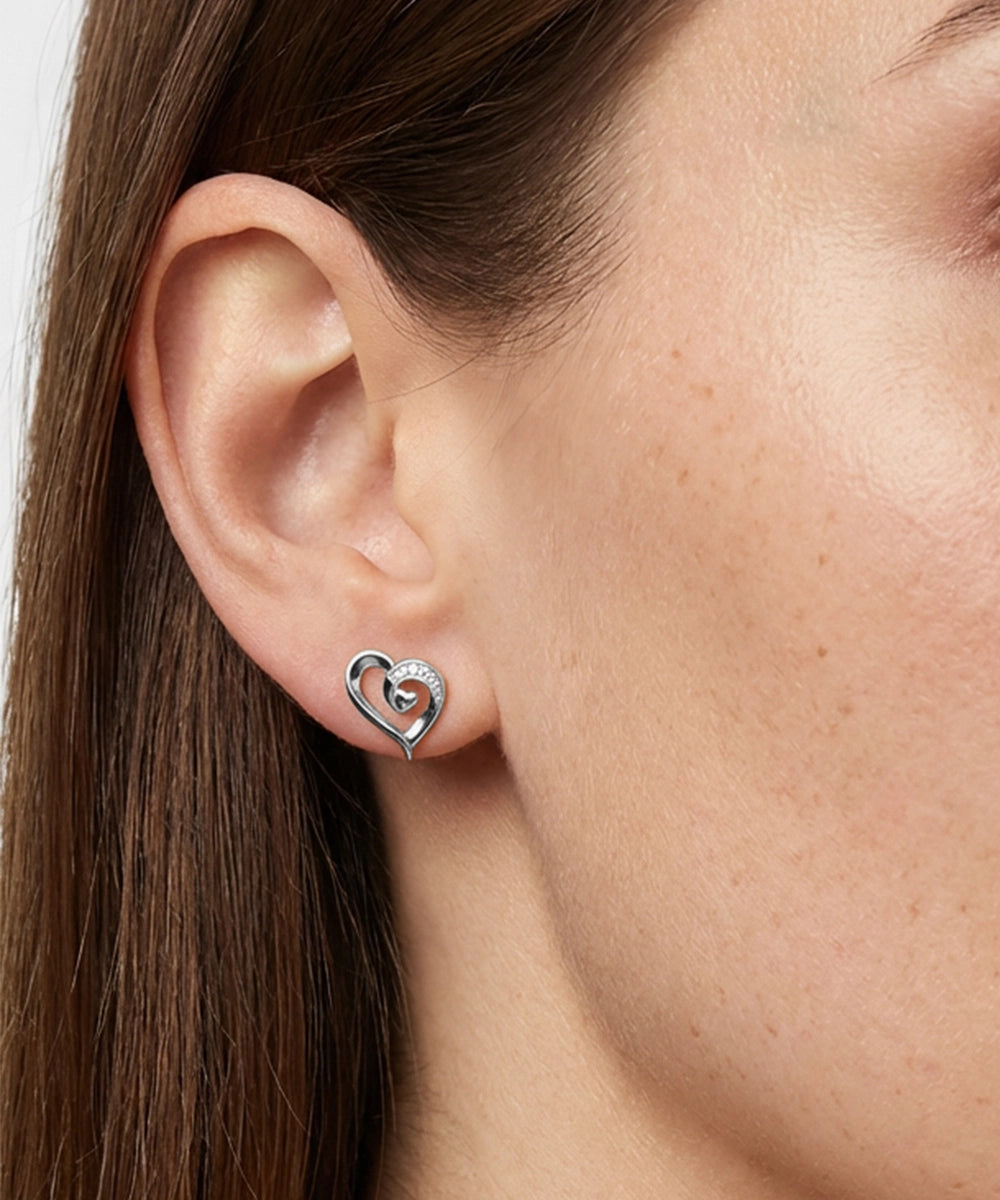 Close-up of a person wearing a silver heart-shaped earring.