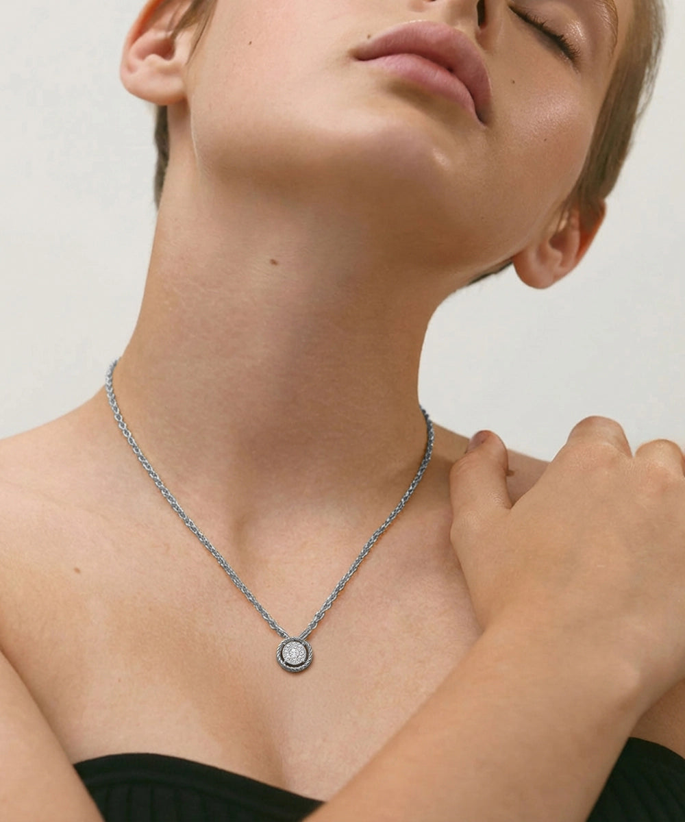 Person wearing a delicate necklace with a small pendant on a neutral background