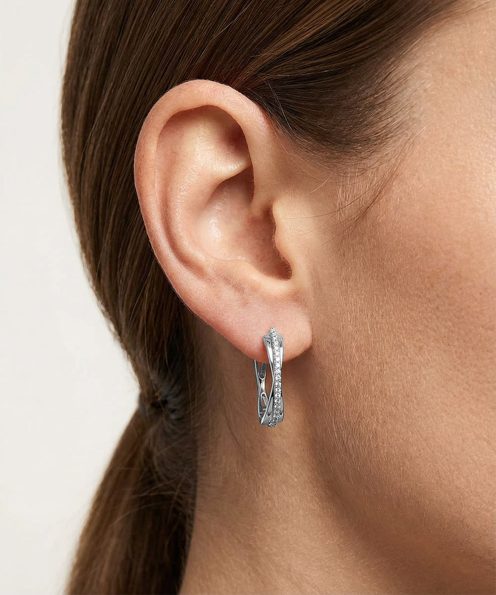 Silver hoop earrings worn by a person with a neutral background