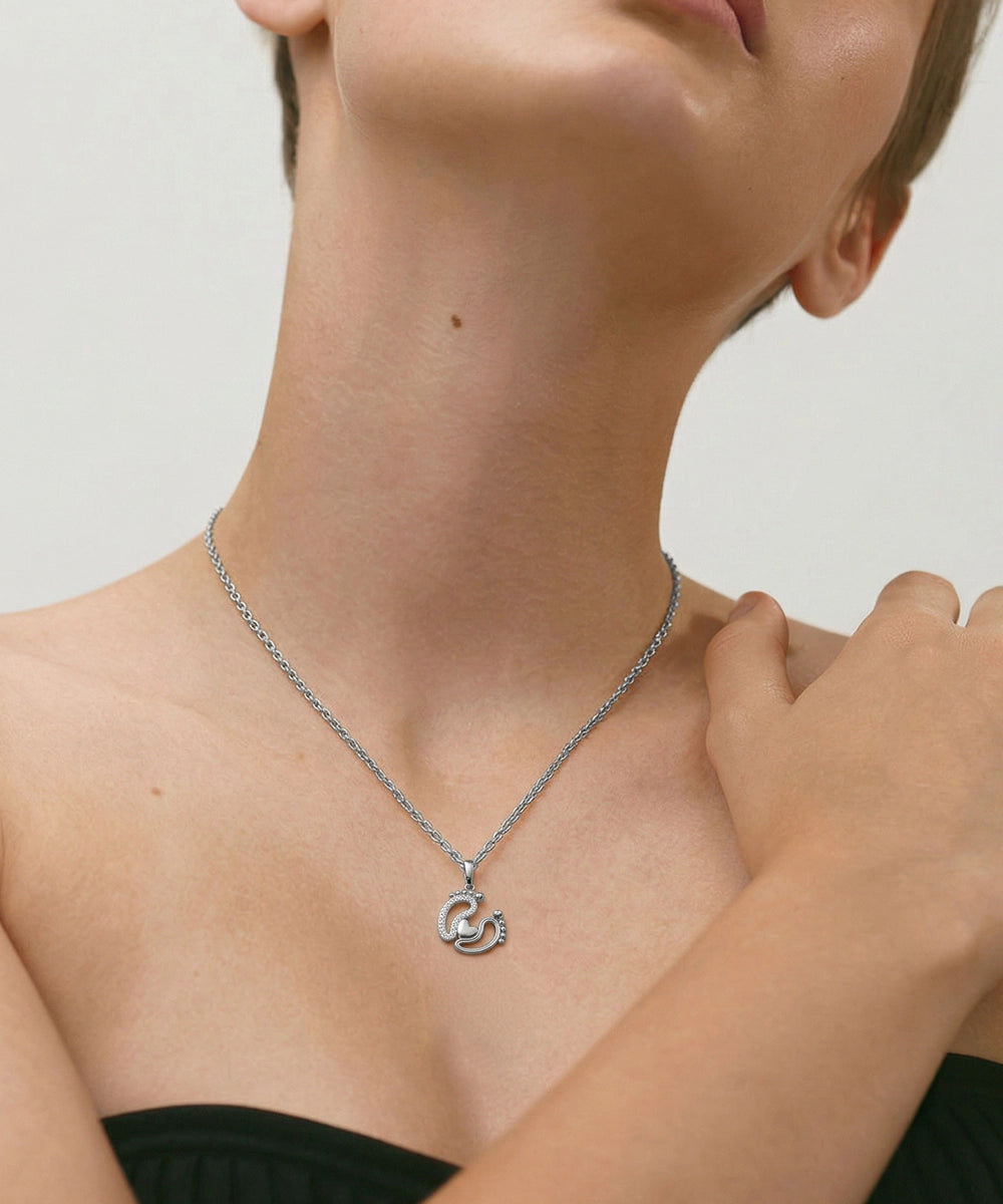 Person wearing a silver necklace with a pendant on a neutral background
