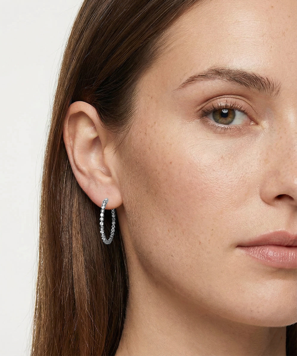 Close-up of a woman wearing hoop earrings with a plain background