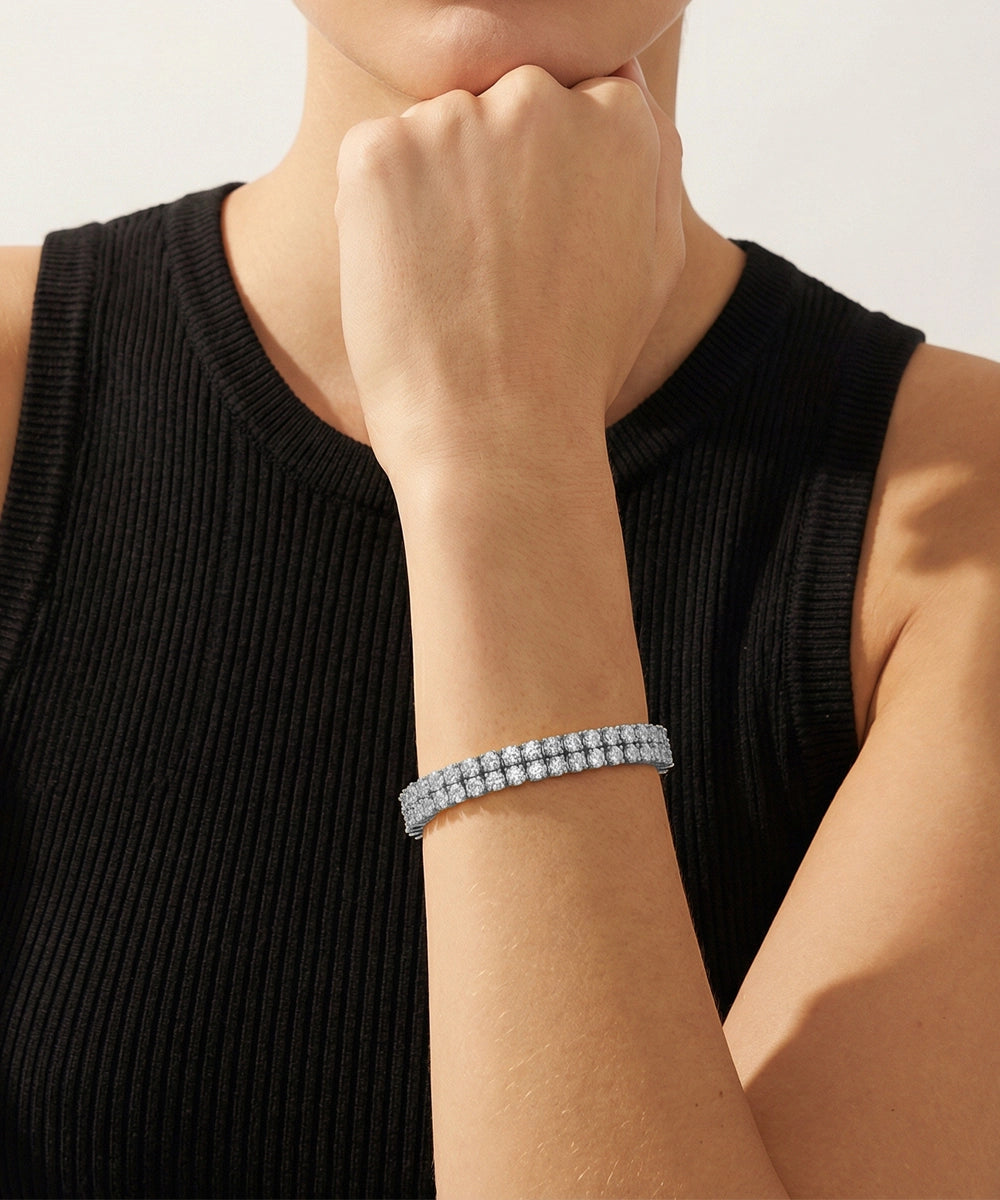 Person wearing a gold bracelet on a plain background