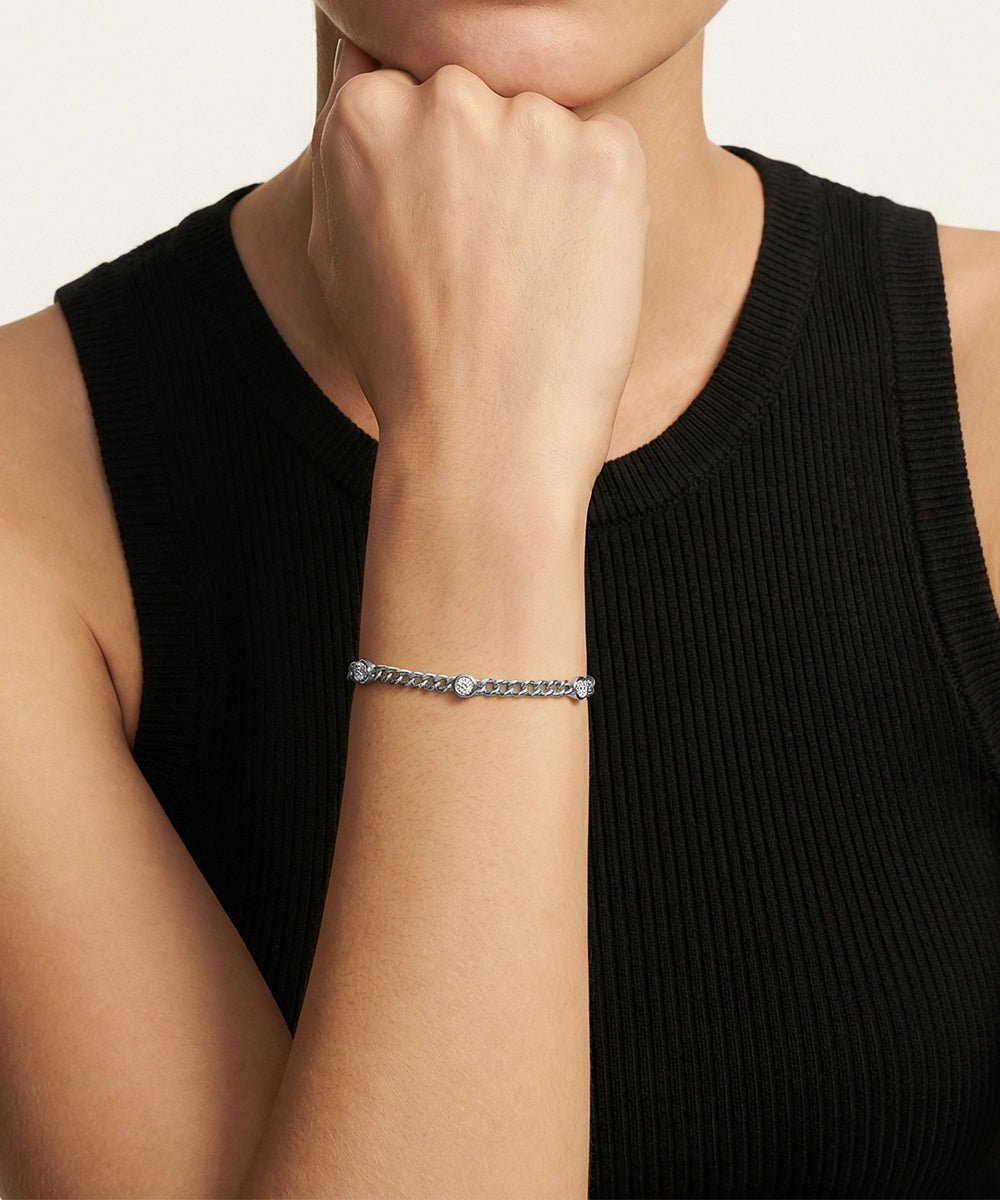 Person wearing a gold bracelet on a plain background