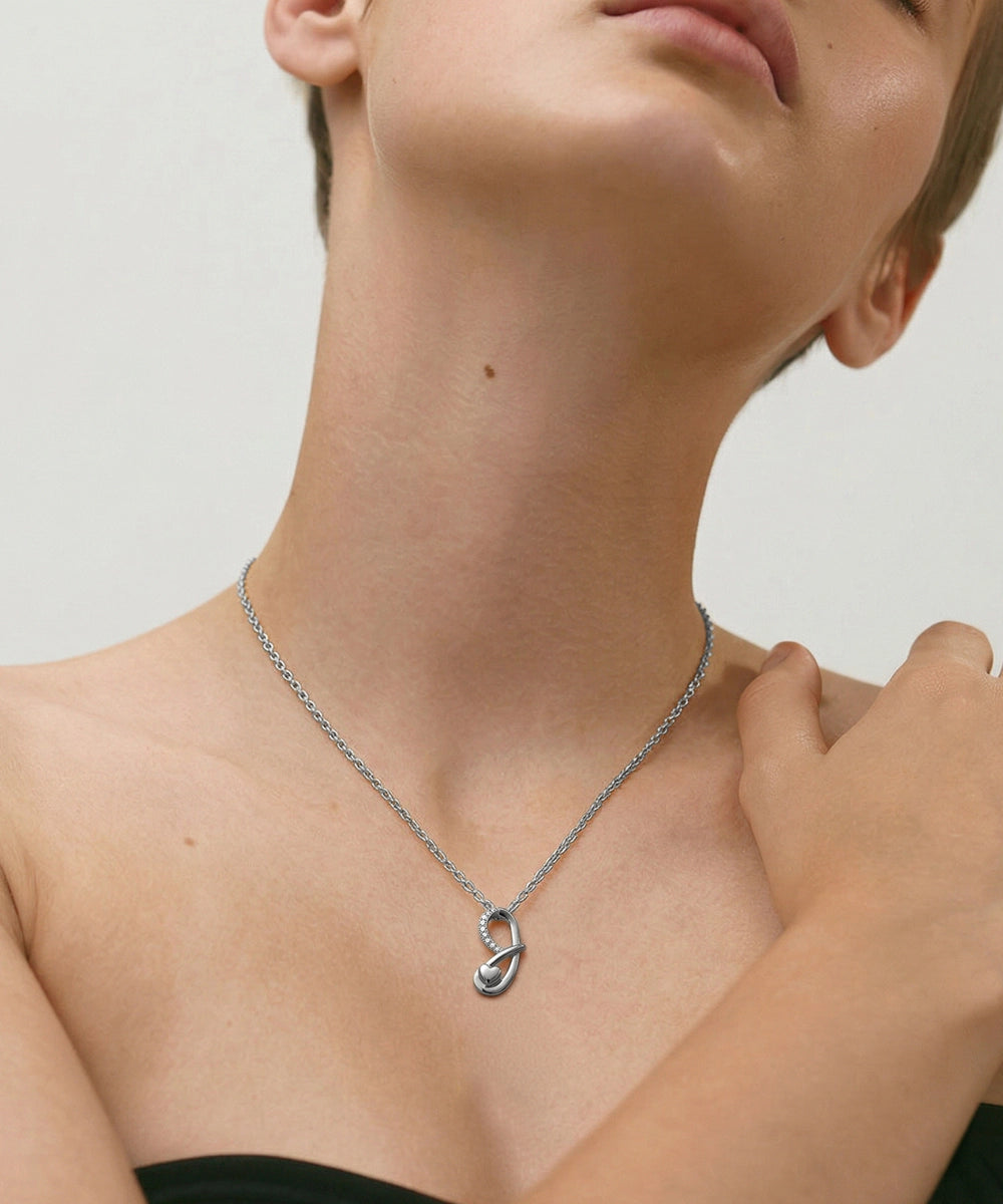 Person wearing a silver necklace with a unique pendant on a neutral background