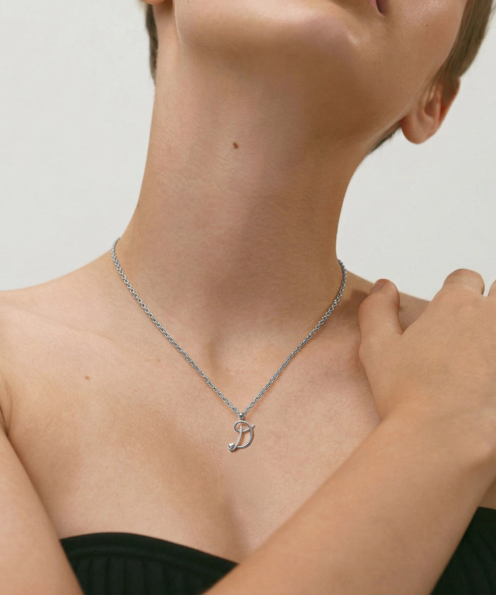 Person wearing a silver necklace with a small pendant on a neutral background