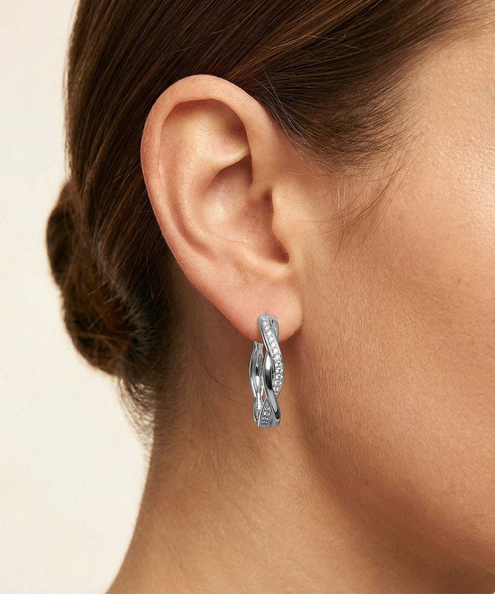 Silver hoop earring worn by a person with a neutral background
