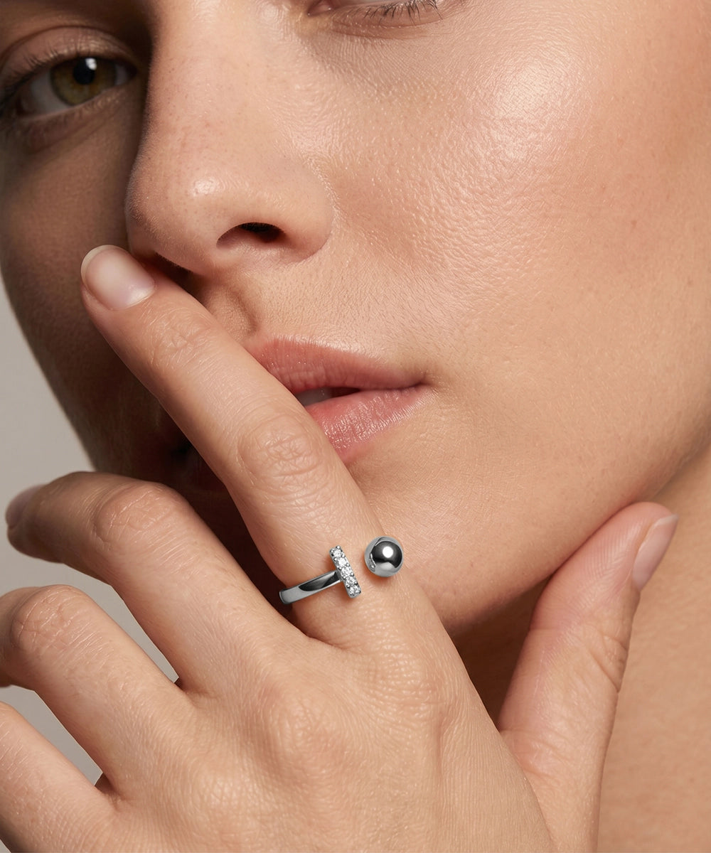 Close-up of a woman's hand wearing a silver ring with a black pearl and small diamonds.