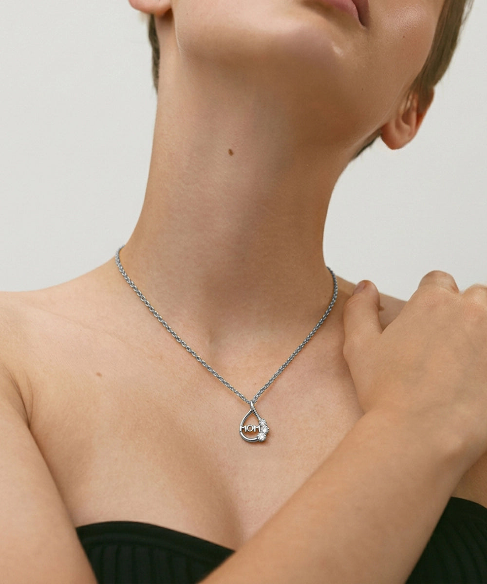 Necklace with a heart-shaped pendant worn by a person against a neutral background
