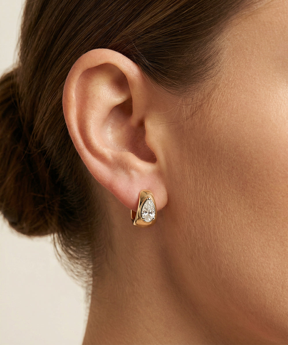 Gold earring worn by a person with a neutral background