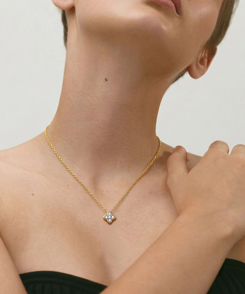Woman wearing a gold necklace with a circular pendant on a neutral background