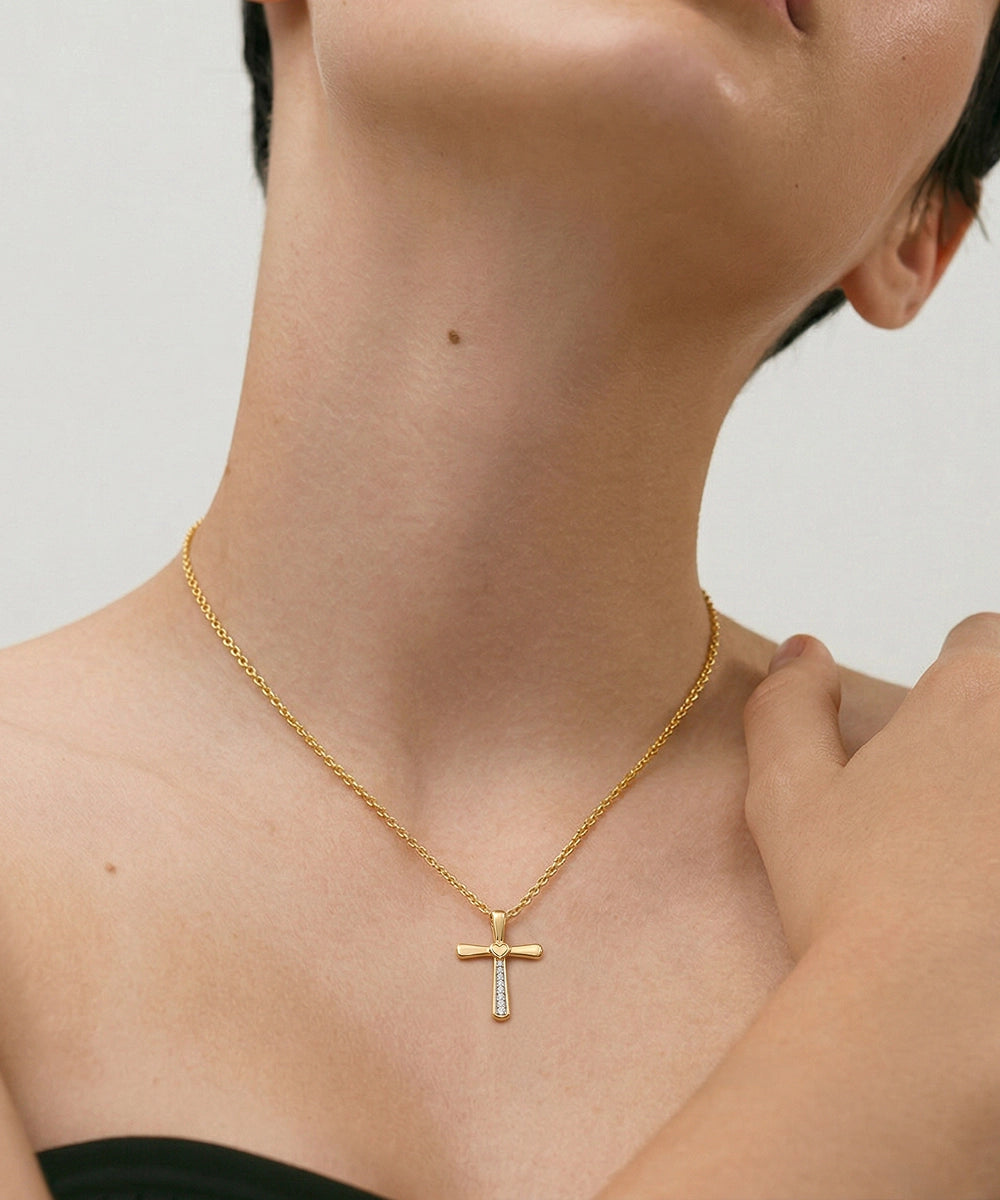 Gold necklace with a cross pendant on a person against a neutral background