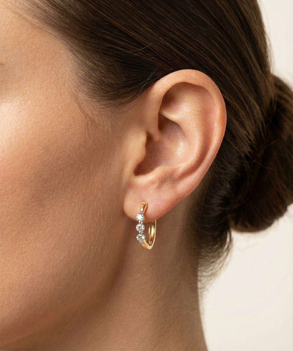 Gold hoop earring with diamonds worn by a person