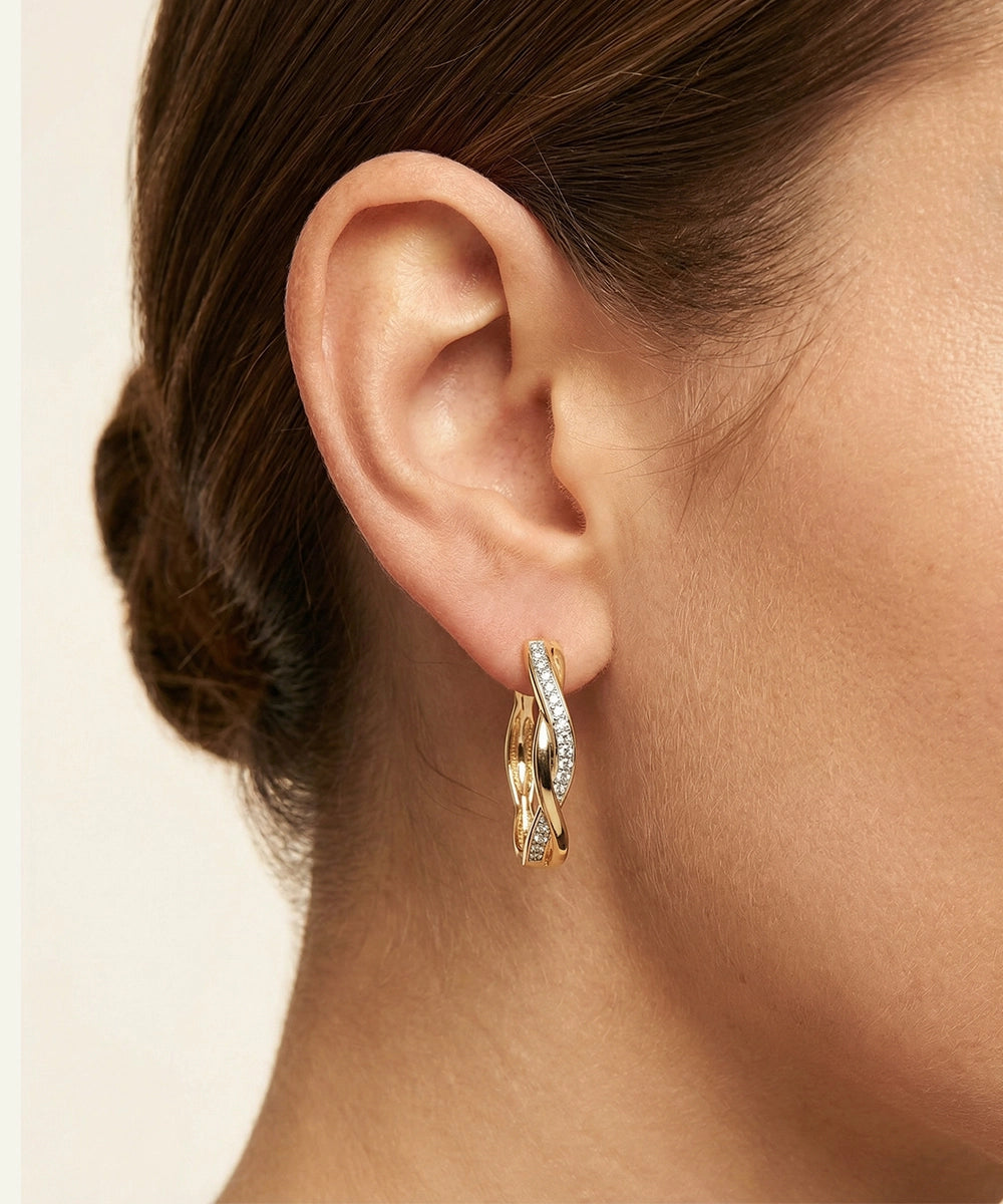 Gold hoop earrings worn by a person with a neutral background