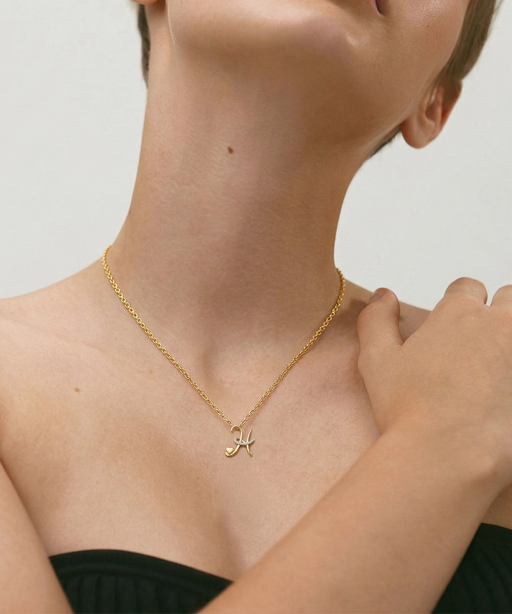 Gold necklace with a cat-shaped pendant worn by a person on a plain background