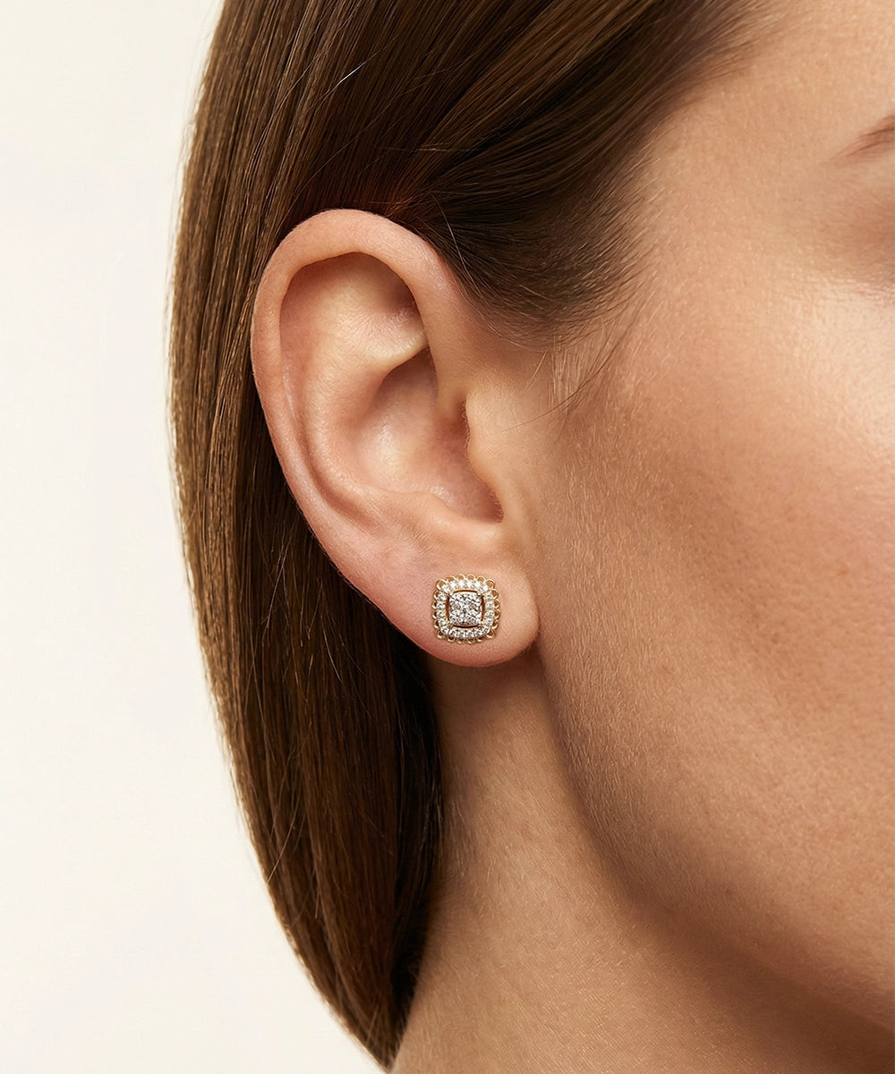 Close-up of an ear wearing a diamond earring on a neutral background