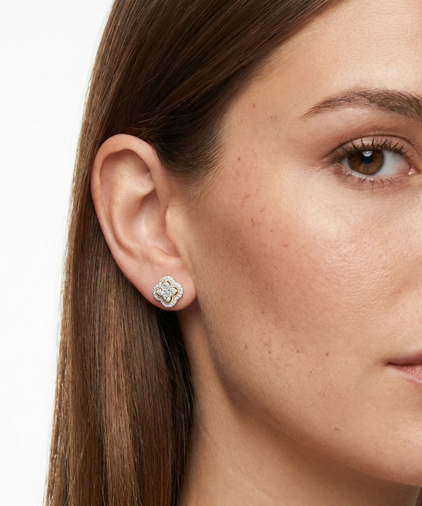 Close-up of a woman wearing diamond stud earrings on a white background