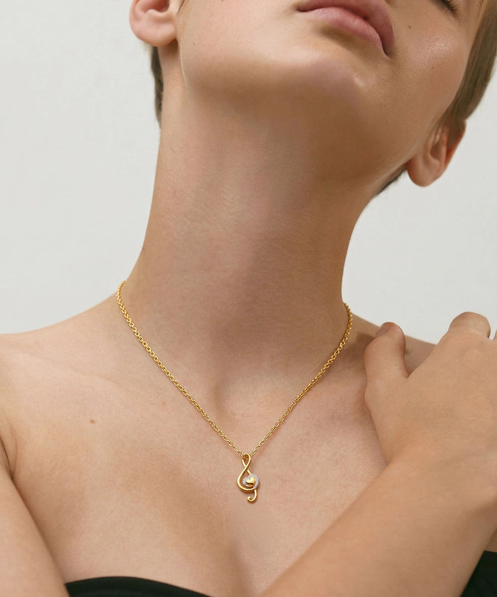 Gold necklace with a unique pendant on a person against a neutral background