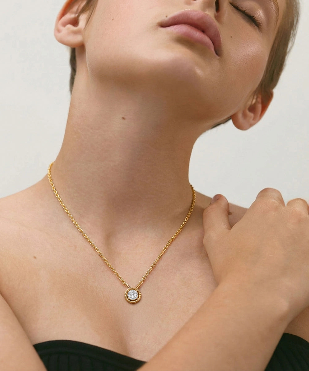 Gold necklace with a pendant worn by a person against a neutral background