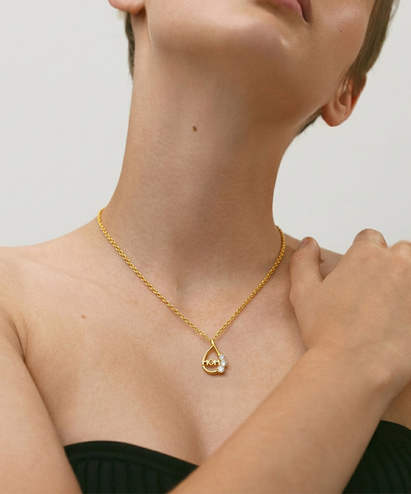 Gold necklace with a pendant worn by a person on a neutral background
