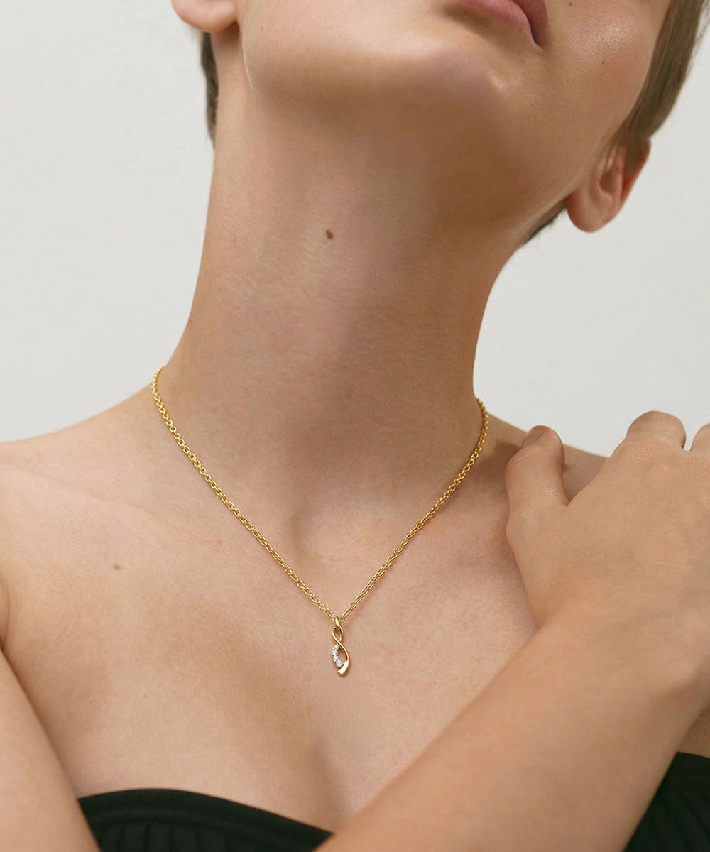 Gold necklace worn by a person on a neutral background