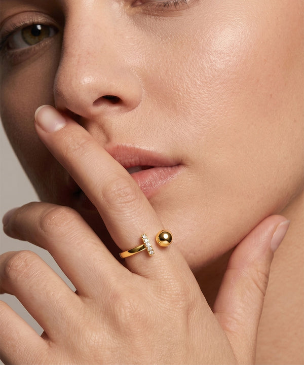 Close-up of a woman's hand with a gold ring featuring a diamond on a neutral background