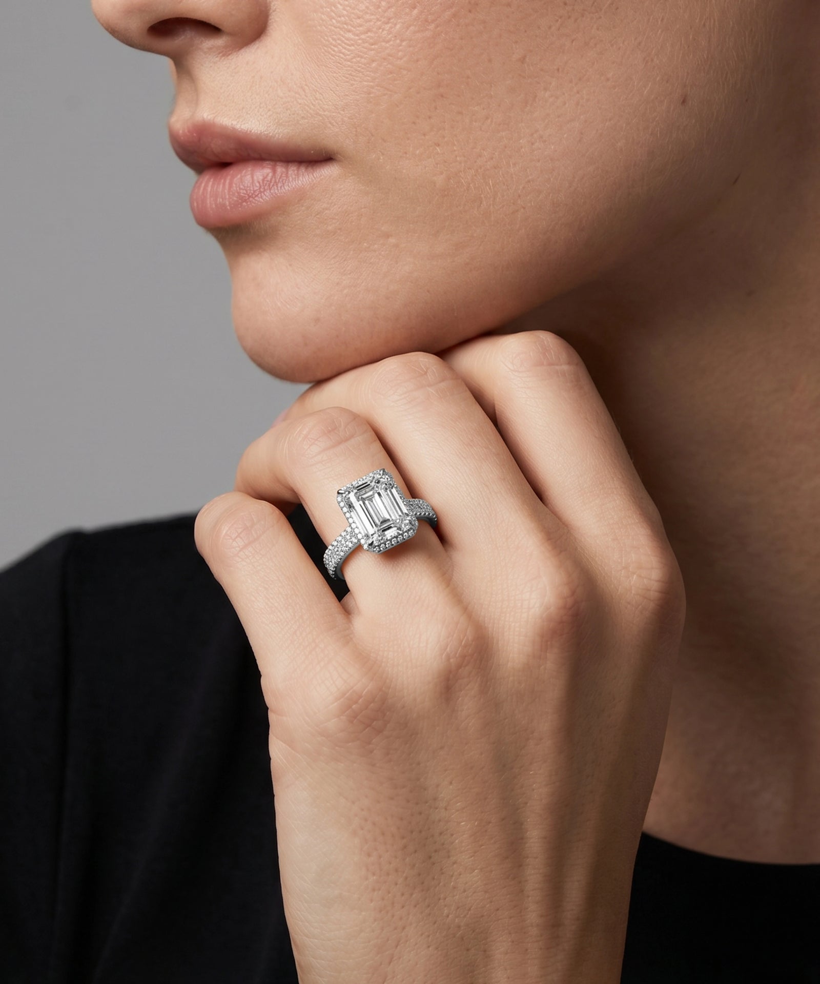 Close-up of a hand wearing a diamond ring with a gray background