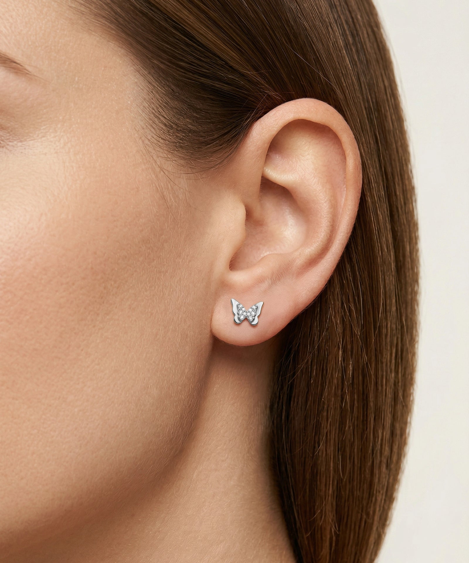 Butterfly-shaped earrings worn by a person with brown hair.