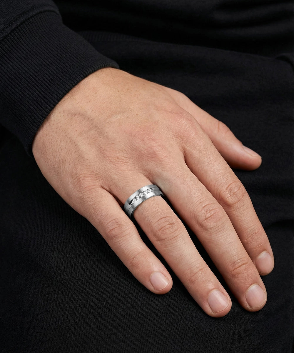 Hand wearing a silver ring on a black background